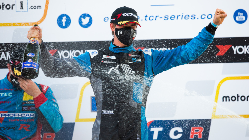 Nicolas Baert celebrates by spraying champagne on the podium whilst wearing a mask