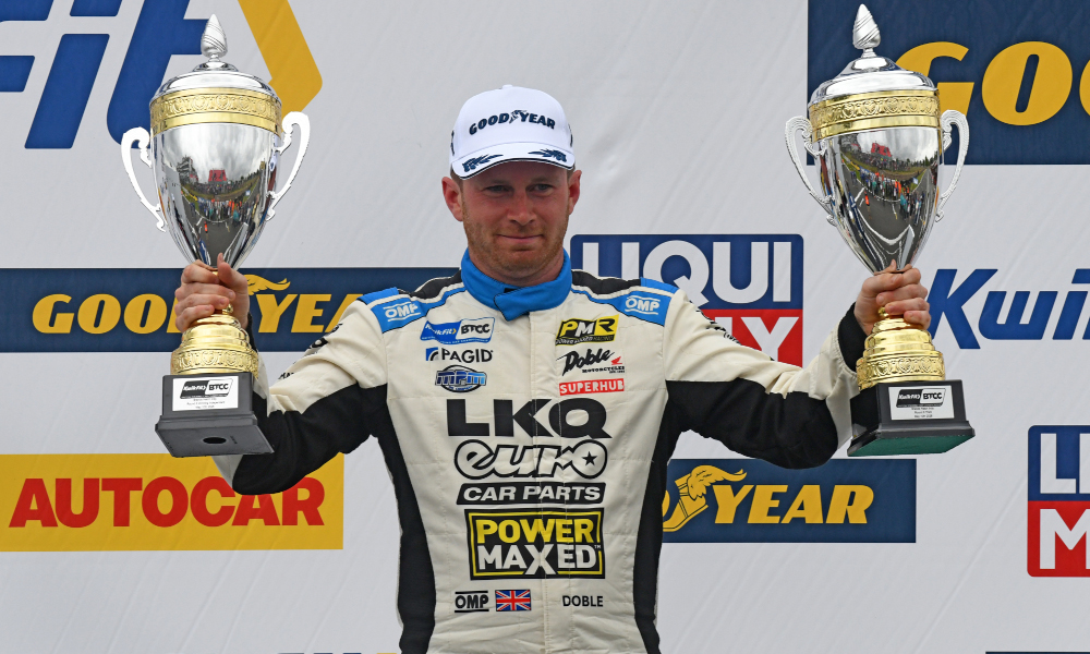 Mikey Doble celebrates with his trophies on the podium